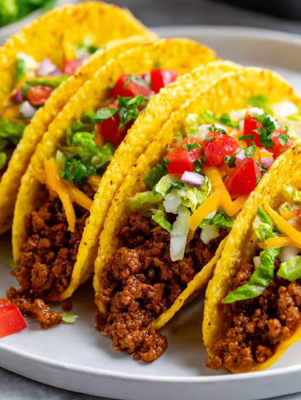 A plate of tacos with lettuce, tomatoes, and cheese.