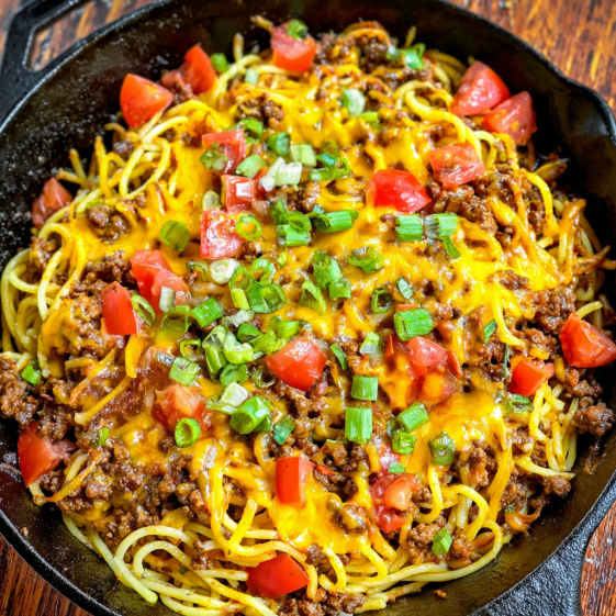 A bowl of spaghetti with meat and tomatoes.