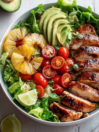 A bowl of food with chicken, tomatoes, avocado, and pineapple.