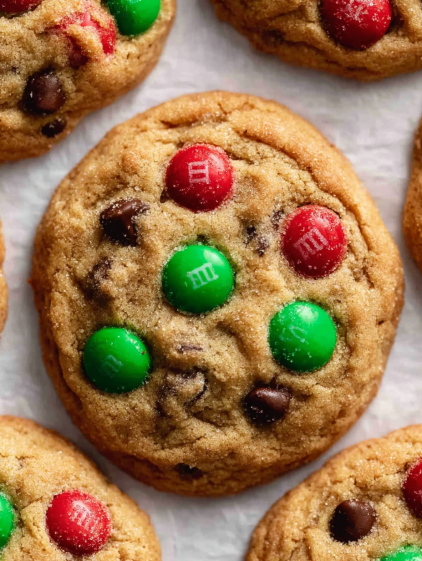 A close up of a chocolate chip cookie with green and red M&M's.