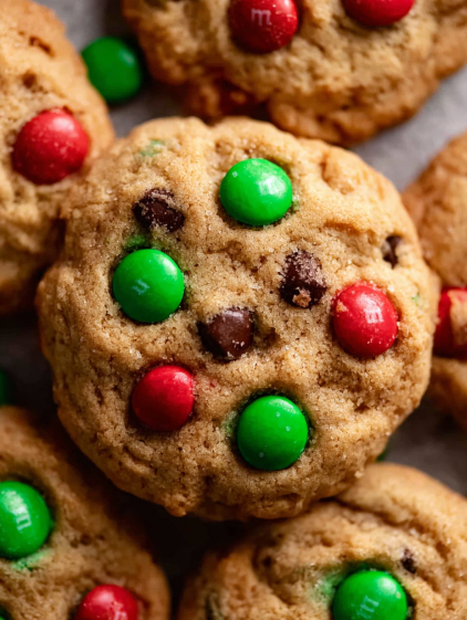 A close up of a chocolate chip cookie with green and red sprinkles.