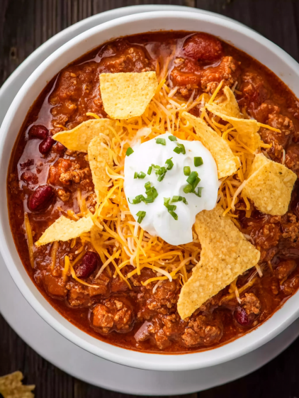 A bowl of chili with a dollop of sour cream on top.