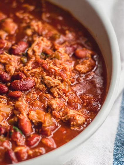A bowl of chili with beans, chicken, and tomatoes.