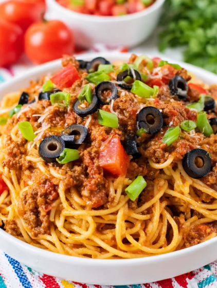 A bowl of spaghetti with meat and black olives.