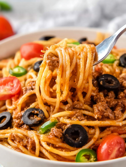 A fork is picking up spaghetti with meat and tomatoes.