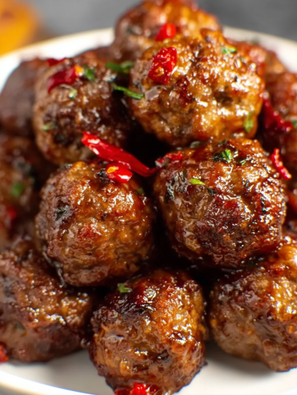 A plate of meatballs with peppers on top.