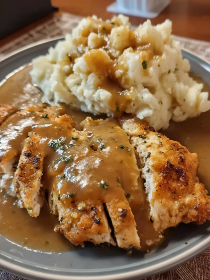 A plate of chicken with gravy and mashed potatoes.