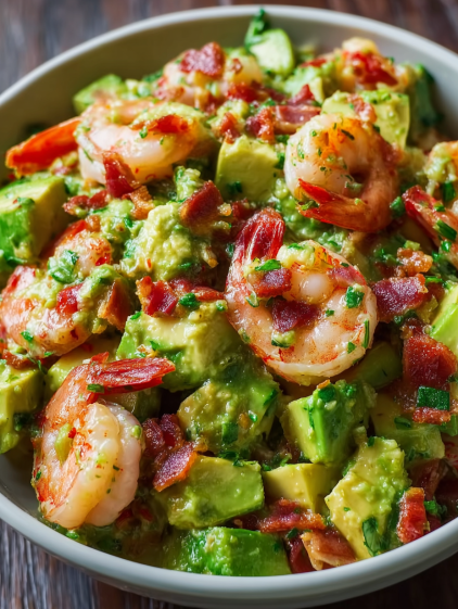 A bowl of shrimp and avocado salad with bacon.