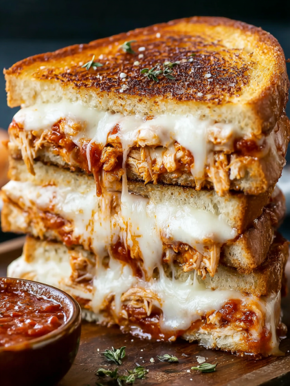 A stack of grilled cheese sandwiches with chicken and tomato sauce.