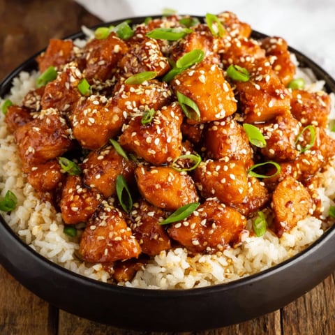 A bowl of chicken with rice and green onions.