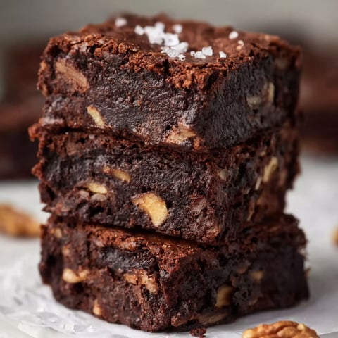 A stack of brownies with nuts on top.