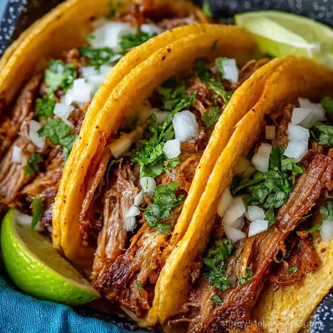 A plate of pork carnitas with onions and limes.